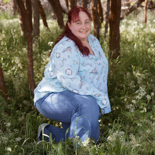 Lisa kneeling in a wooded area in a light blue shirt with Cinderella images